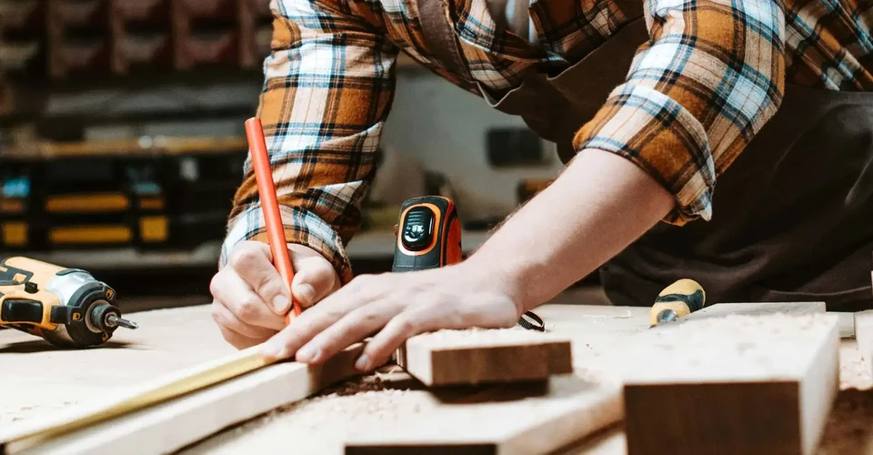 Chantier extérieur, artisan à genoux travaillant sur planches de bois brut